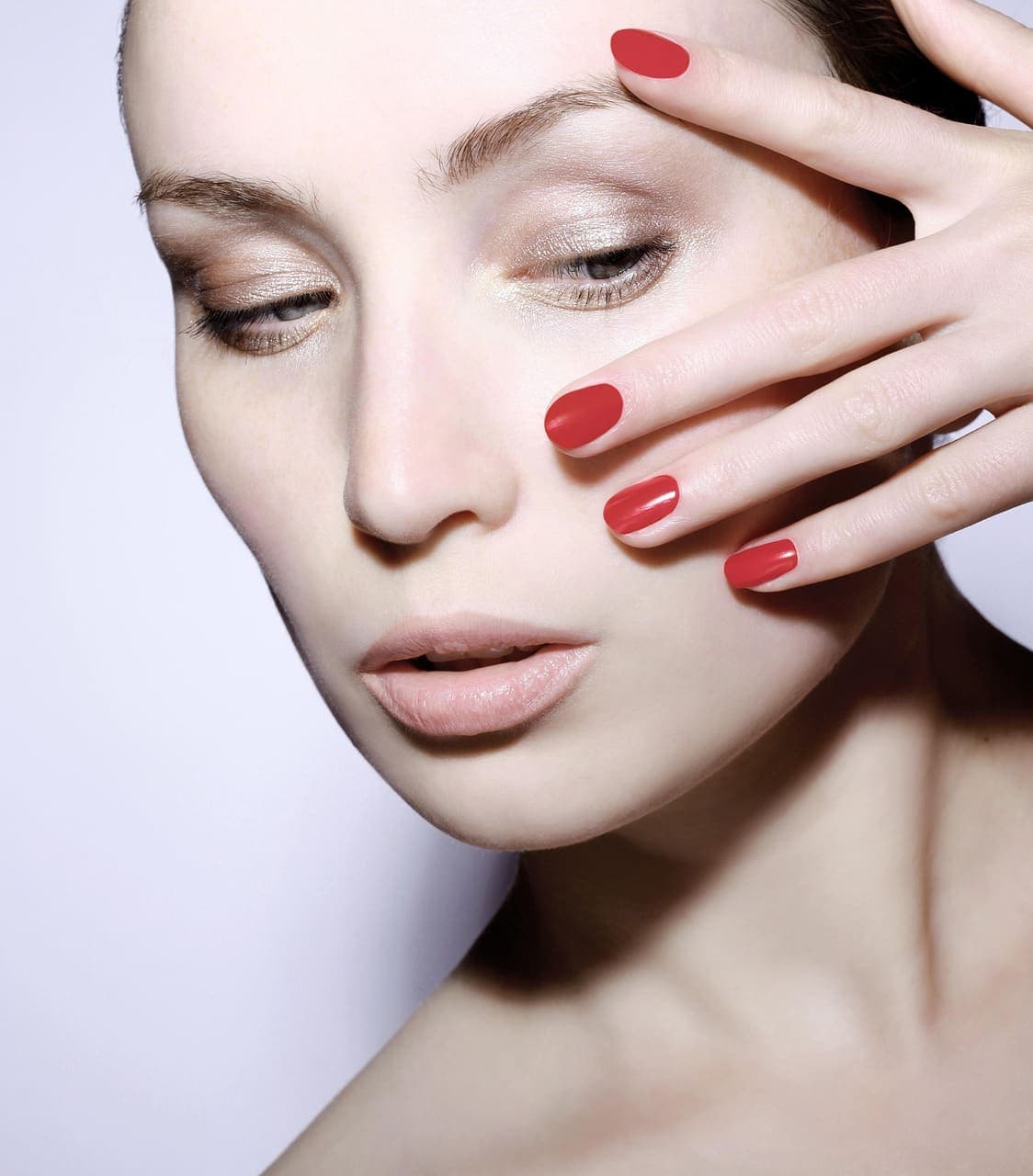 Red manicured nails held up to the face